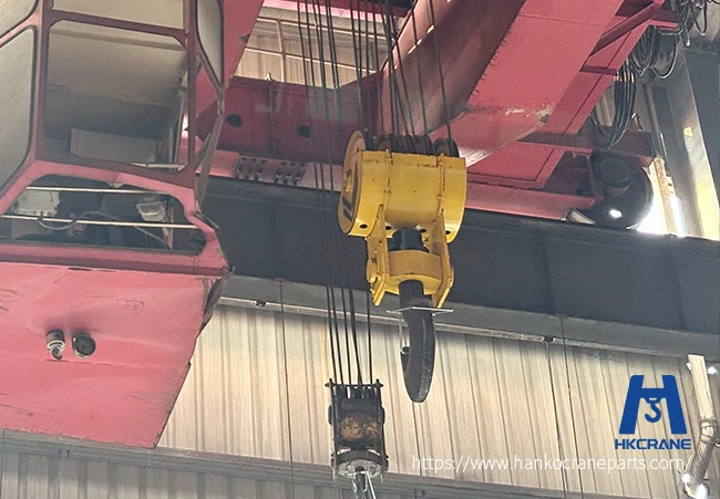 Overhead crane hook carrying heavy industrial load in manufacturing facility